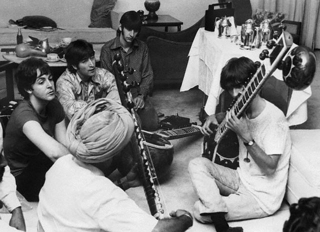 Musician George Harrison Receiving Sitar Lesson. Beatle George Harrison receiving instruction in playing the sitar from a Sikh teacher as the other members of the Beatles look on in quiet fascination. July 5, 1966. New Delhi, India.